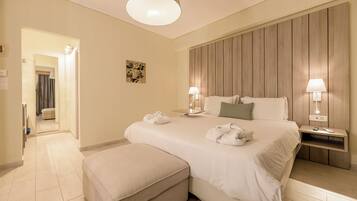 A hotel room with a large bed, two bedside tables with lamps, a wooden headboard, and a small bedside table with a book.