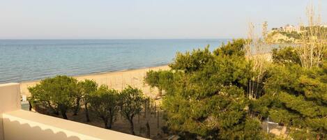 A balcony with a view of a beach and the sea.