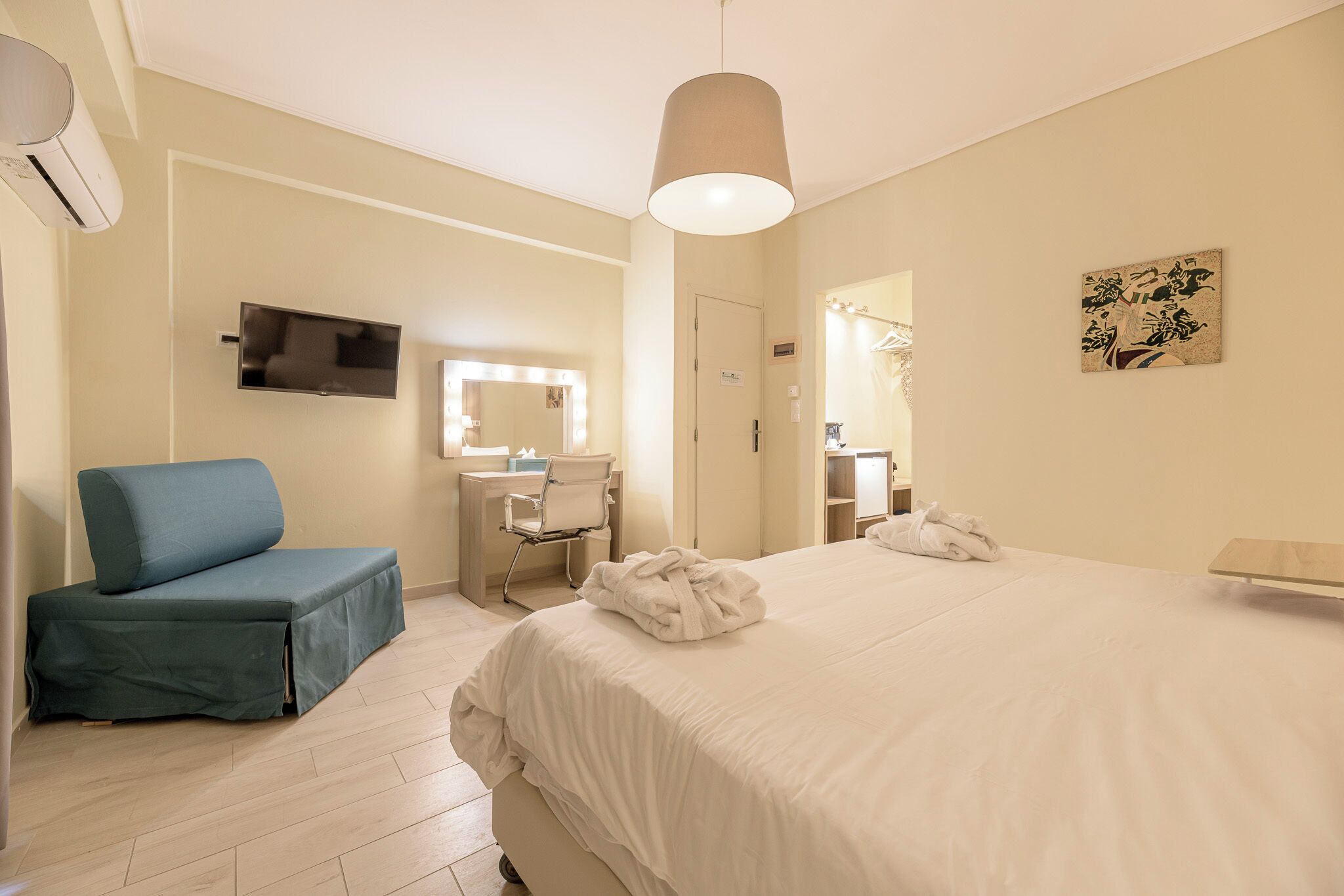 Une chambre d’hôtel comprenant un lit, un coin salon, une coiffeuse avec un miroir et un téléviseur.