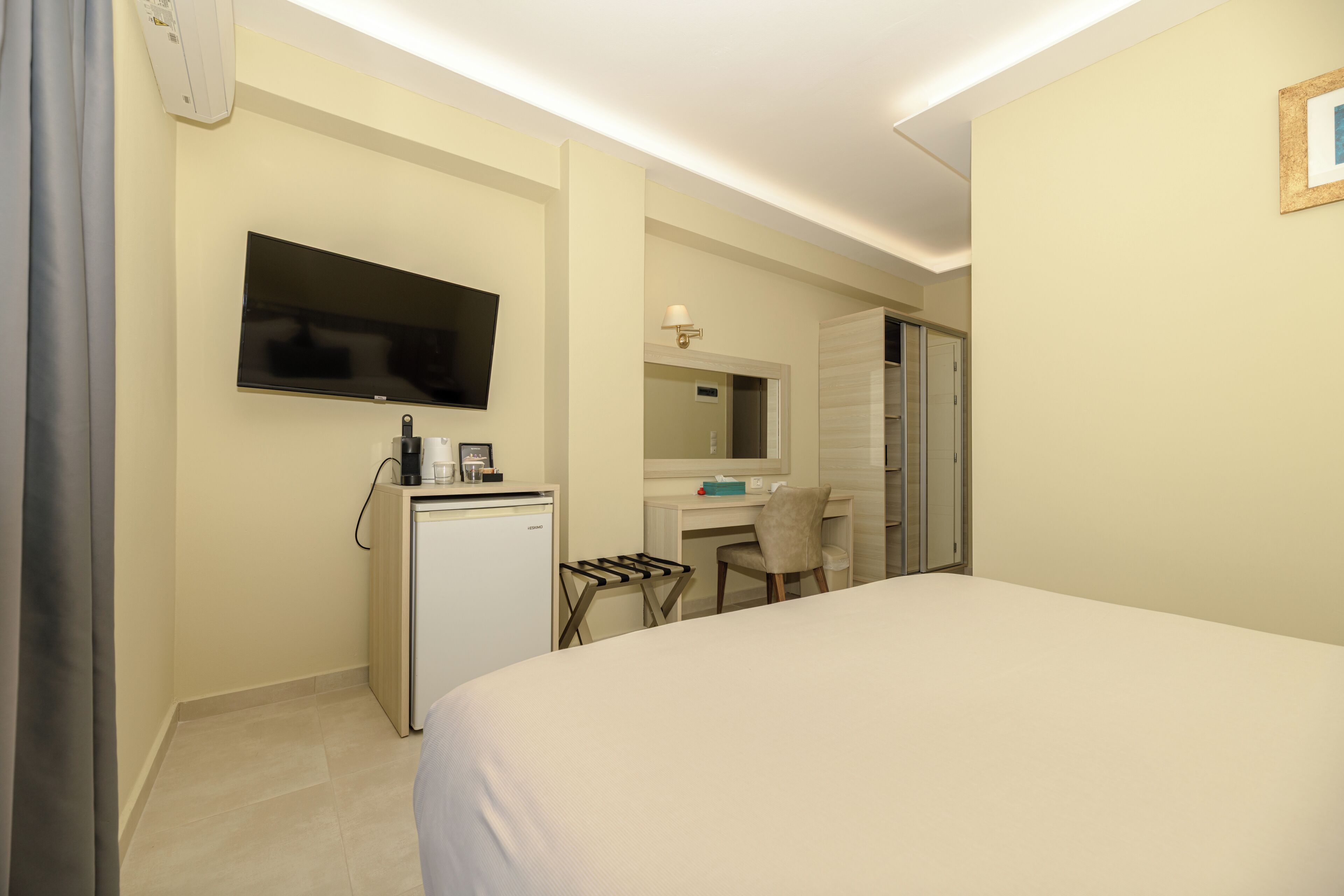 A hotel room with a bed, a desk with a chair, a television, a mini-fridge, and a microwave.