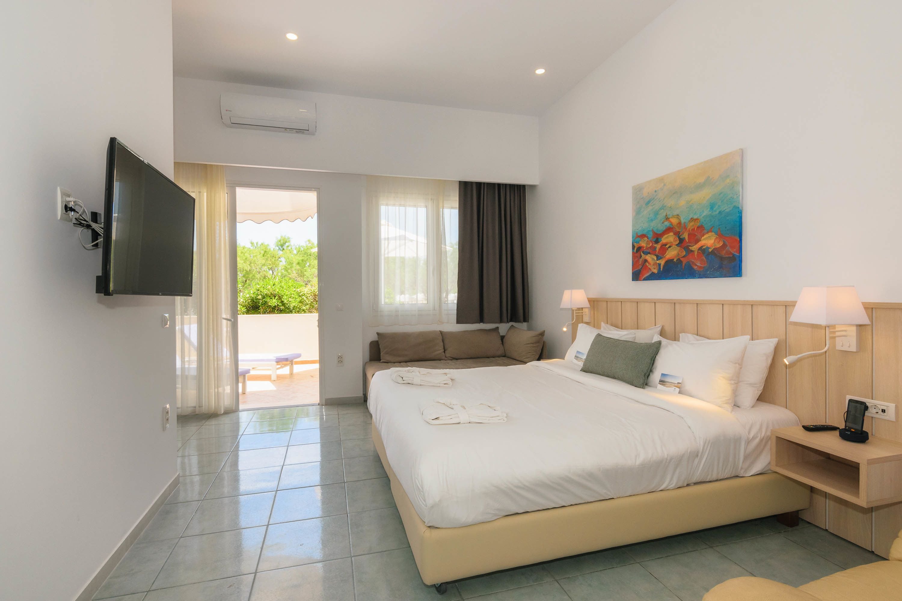 A hotel room with a large bed, a flat-screen TV, a painting on the wall, and a view of the outdoors through the window.