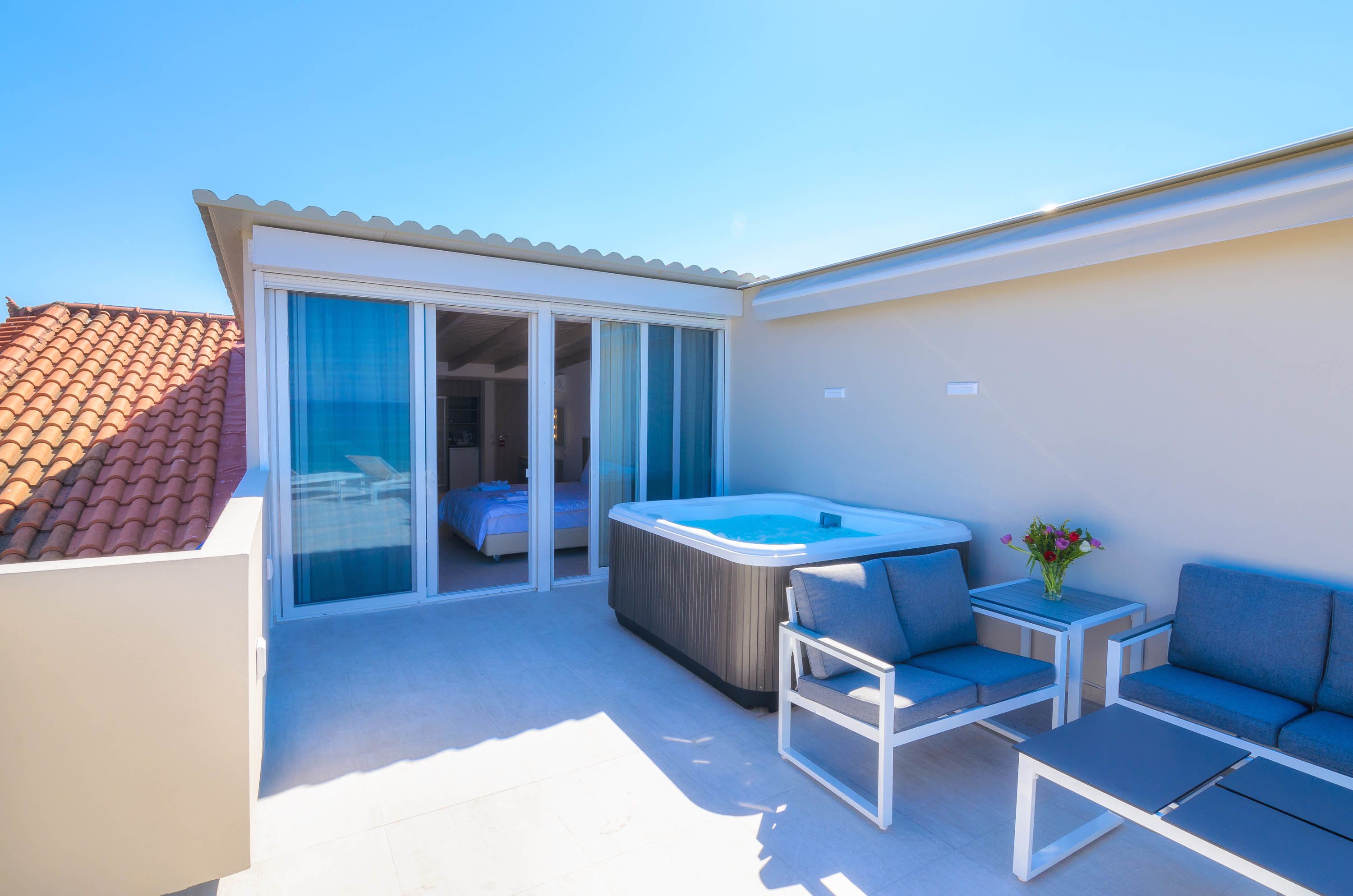 Een balkon met een jacuzzi, een bed en een zithoek met een tafel en stoelen.