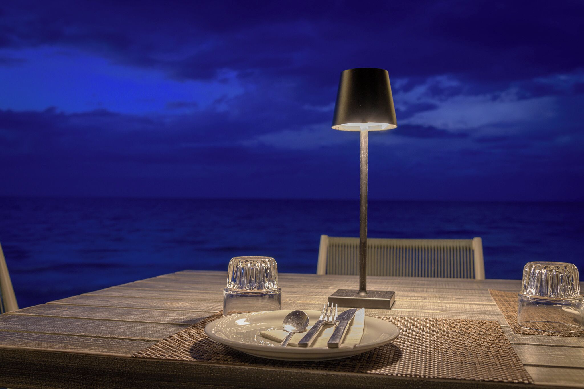 A table set for two with a view of the ocean at night.