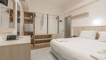 A hotel room with a bed, a desk, a wardrobe, and a mirror.