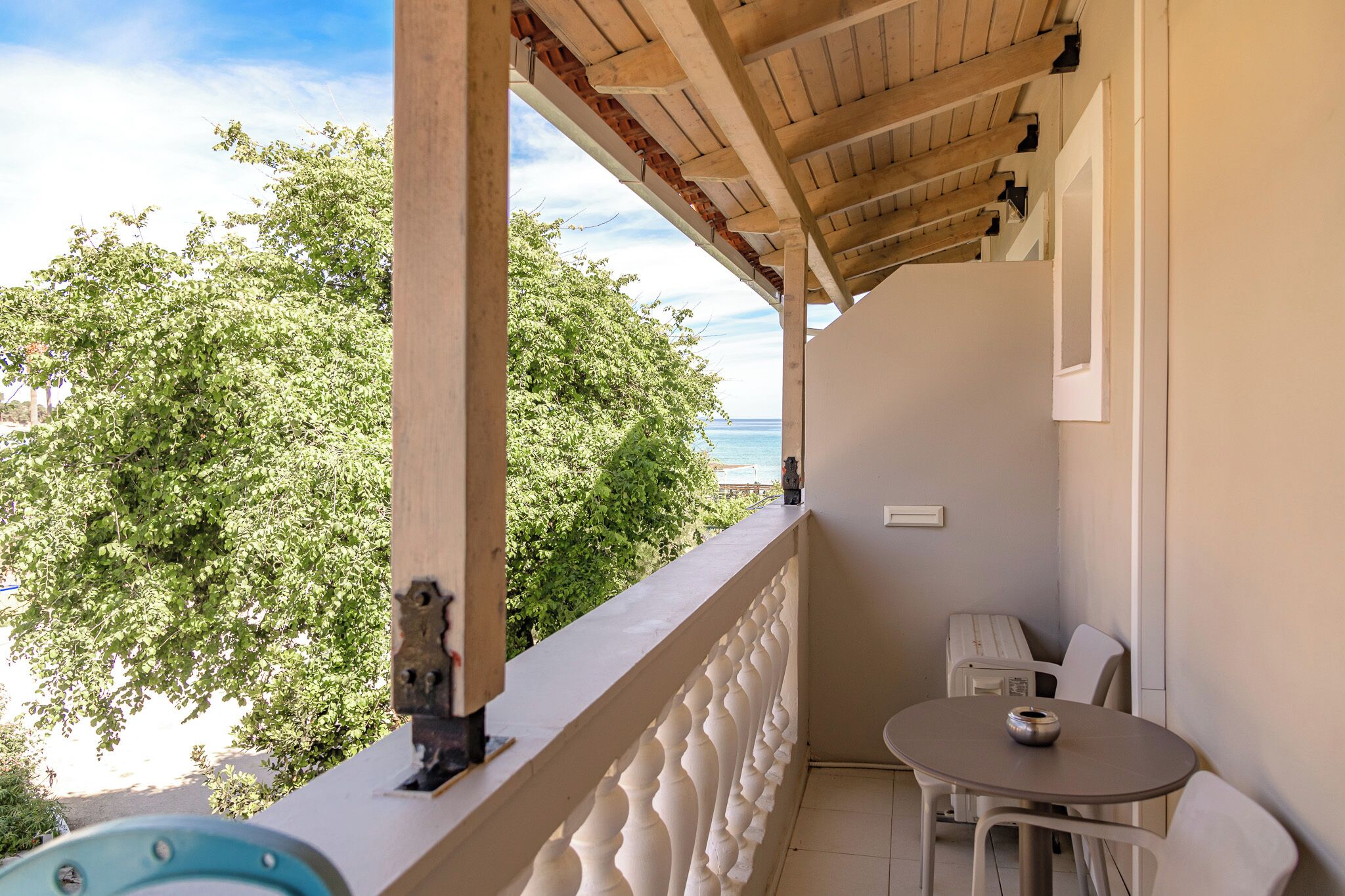 A balcony with a view of the sea, a table with chairs, and a decorative item on the railing.