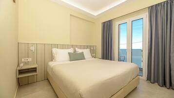 Una habitación de hotel con una cama grande, una mesita de noche, un enchufe y vistas al exterior a través de una puerta corrediza.