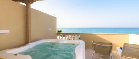 Un jacuzzi con vista al mar, una silla y piso de baldosas.