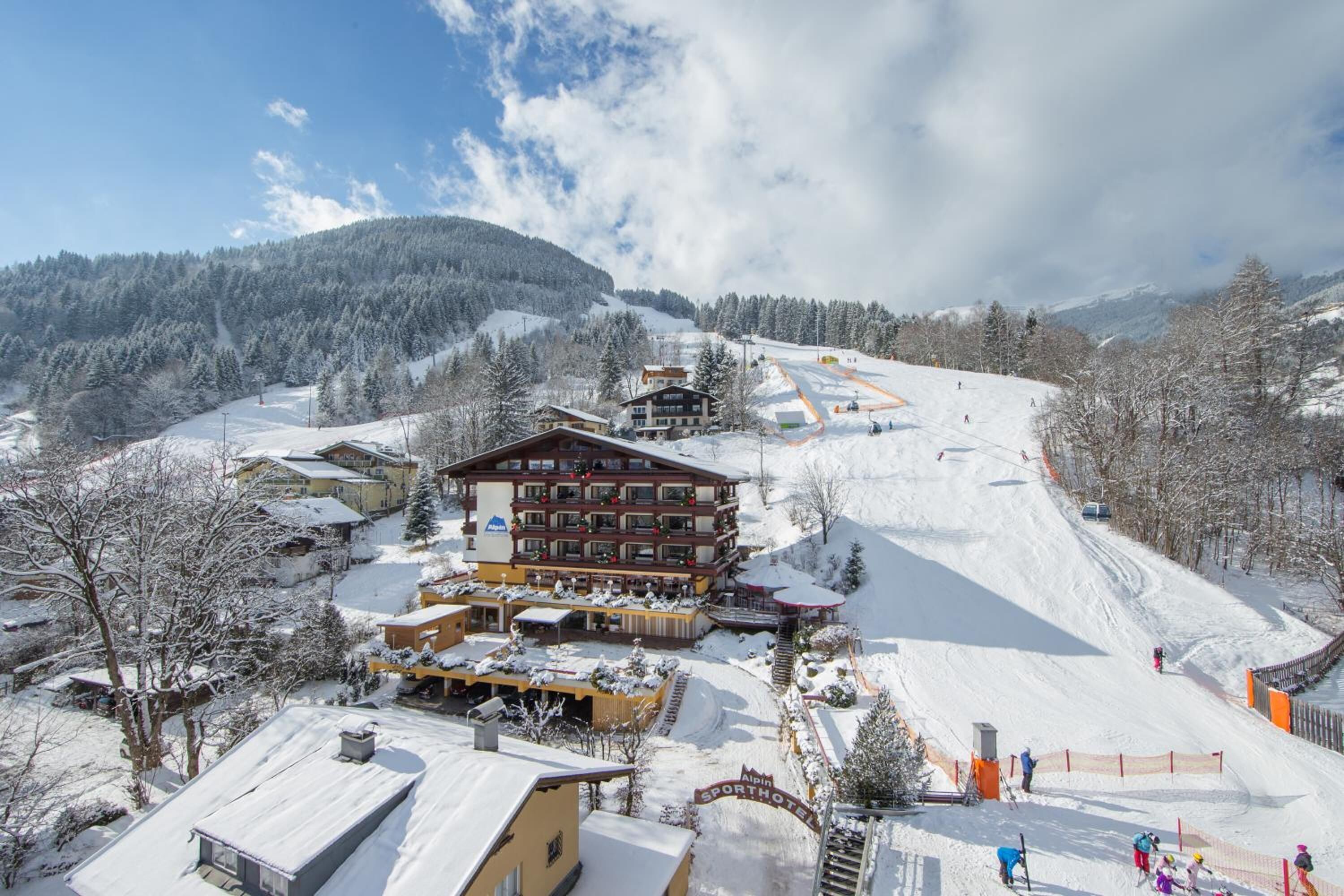 Un centro de esquí con un gran refugio, pistas de esquí y árboles cubiertos de nieve.