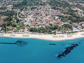 Vista aérea de un pueblo costero con playa, casas y una carretera.