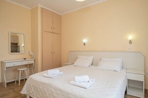 Un dormitorio con cama, escritorio, espejo y dos lámparas de pared.