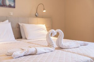 Una habitación de hotel con cama, almohadas y una lámpara fijada a la pared.