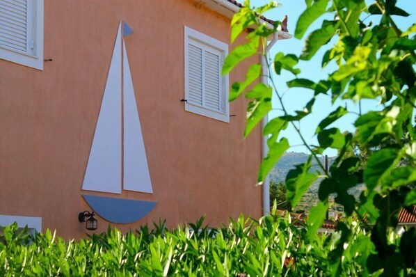 A building with a sailboat cutout on the wall, shutters, and a lantern. - Paspalis Hotel (Kefalonia)