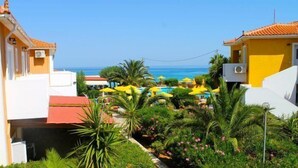 Um resort com área de piscina, palmeiras e vista para o oceano.