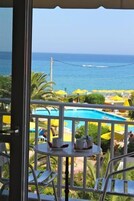 Un balcón con vistas al océano, una piscina y sombrillas amarillas.