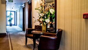 A hotel hallway with a large mirror, a table with chairs, and a potted plant. - Grand Work Hotel (Ankara)