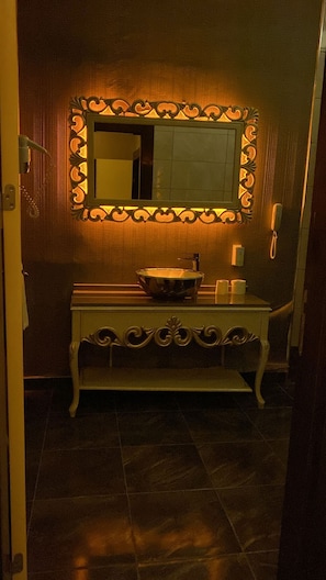 A bathroom with a vanity, a mirror with decorative lights, a sink, and a toilet. - Grand Work Hotel (Ankara)