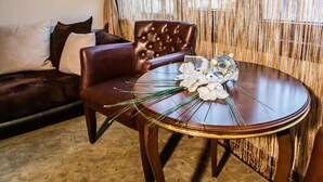 A dining area with a round table, a leather chair, and a sofa with cushions. - Grand Work Hotel (Ankara)