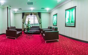 A hotel room with a red carpet, a brown leather sofa, two armchairs, a glass coffee table, and a green plant. - Grand Work Hotel (Ankara)
