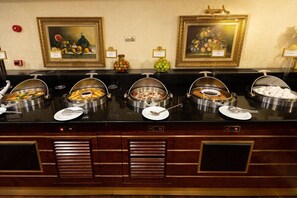 A buffet with various food items and two framed paintings on the wall. - Ilci Residence (Ankara)