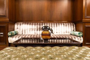 A room with a striped sofa, a glass-top coffee table, and a tufted leather ottoman. - Ilci Residence (Ankara)