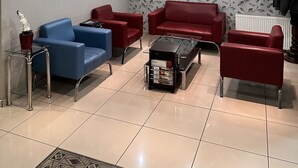 Ein modernes Wohnzimmer mit einem blauen Sofa, roten Sofas, einem Couchtisch und einem dekorativen Spiegel.