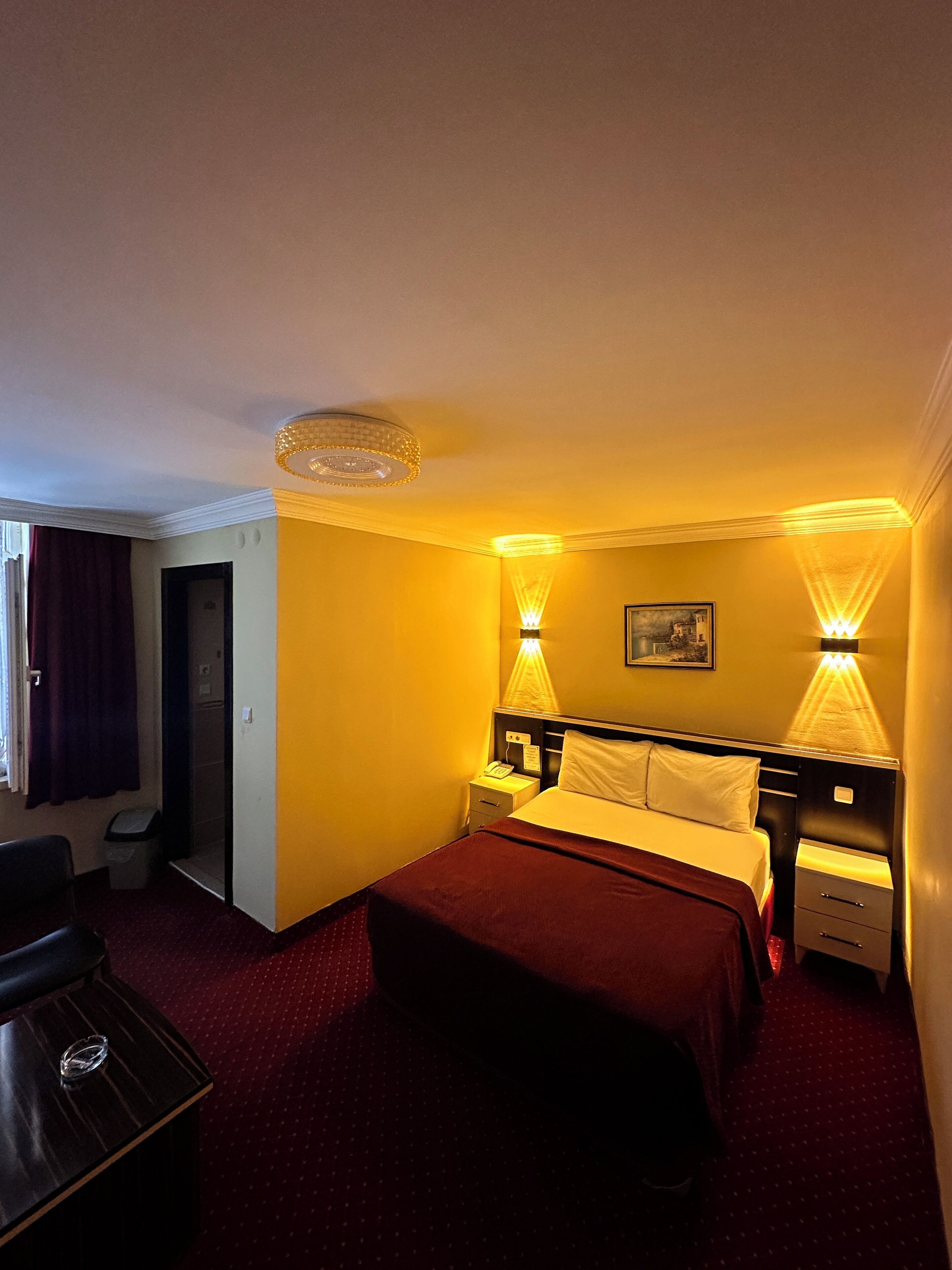 A hotel room with a bed, bedside tables, a desk, and a chair.