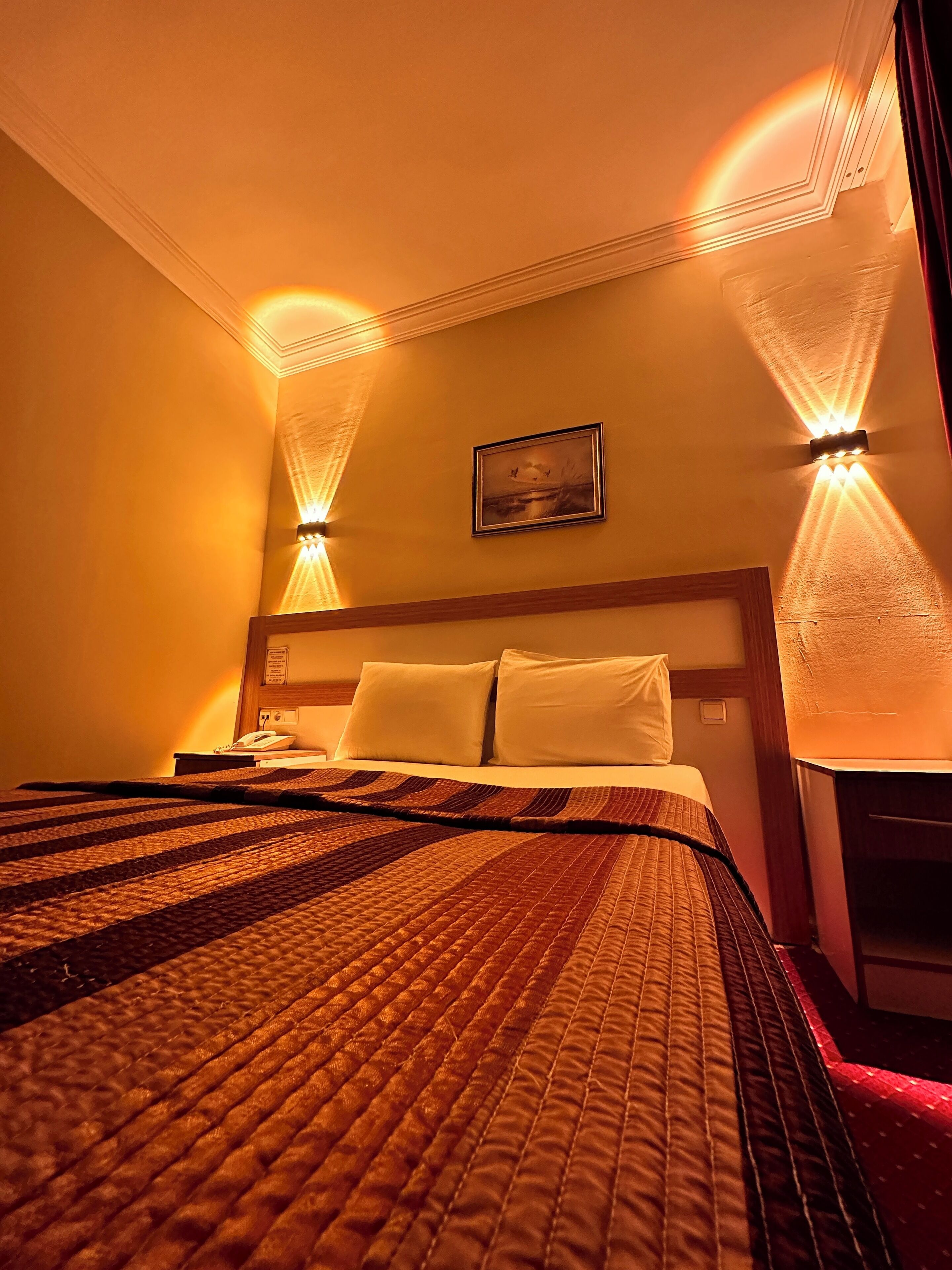 Una habitación de hotel con una cama grande, dos mesitas de noche y un cuadro colgado en la pared.