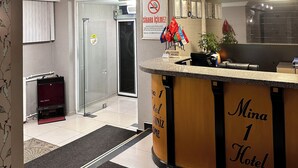 Ein Empfangsschalter mit Schildern, die ein Rauchverbot und das Mina Hotel bewerben.