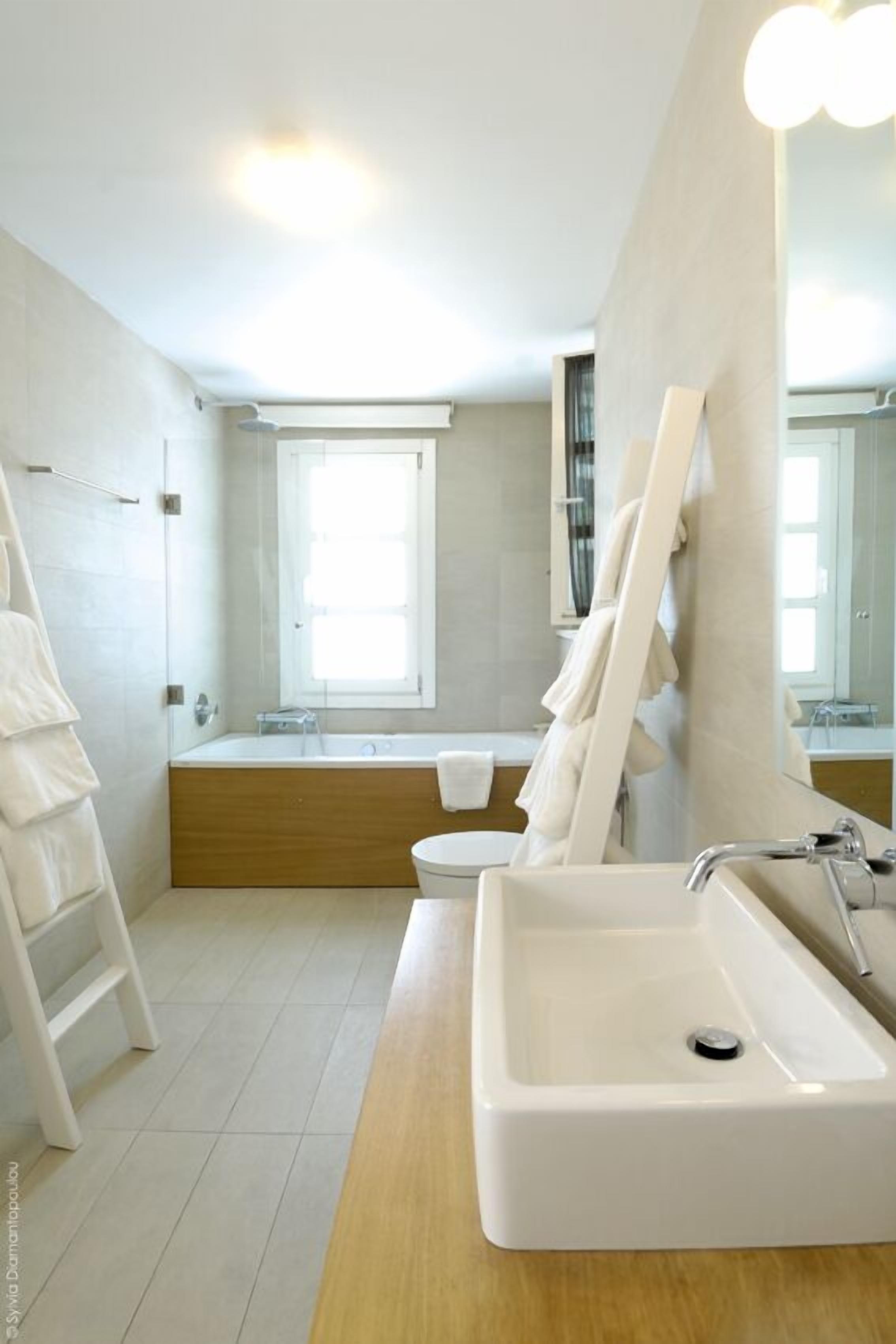 Une salle de bain moderne dotée d’un grand lavabo, d’une baignoire et d’une fenêtre laissant entrer la lumière naturelle.