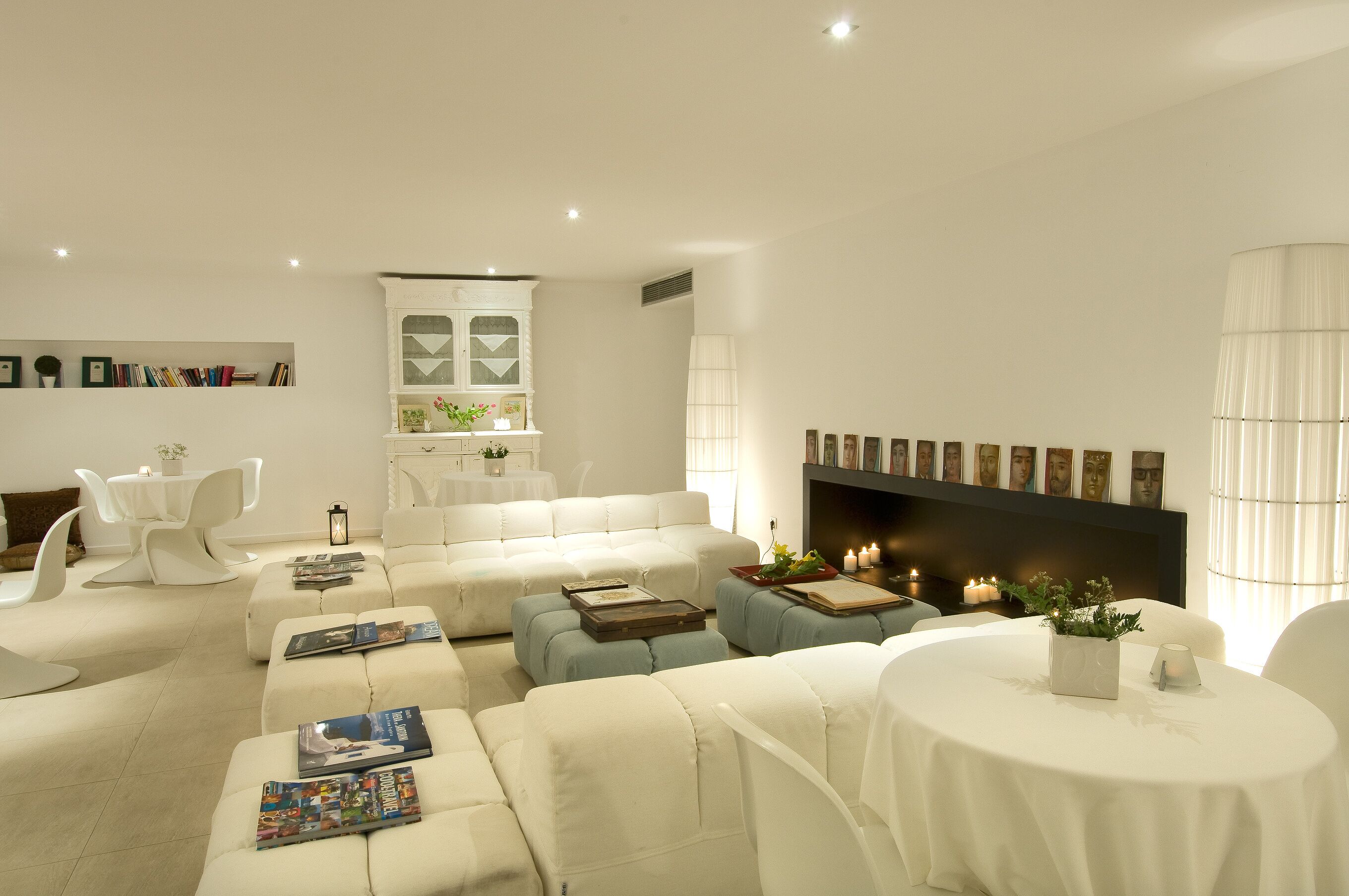 Una sala moderna con sofá, otomanas, chimenea y comedor.