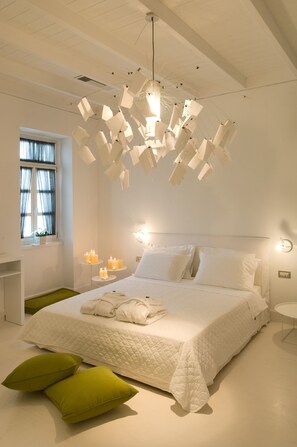 Una camera da letto moderna con un letto grande, un lampadario originale e una finestra con tende leggere.