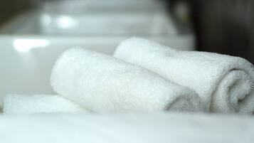A row of neatly folded white towels on a white countertop in a bathroom.