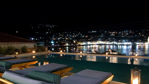 Vista nocturna d'una zona de piscina amb gandules i un fanal.