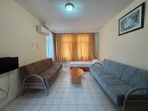 A living room with two sofas, a coffee table, a TV, and a bed with curtains. - Elegant Baronessa Apart Hotel (Alanya)
