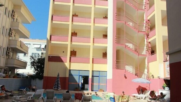 Een meerlaags hotel met een zwembad, inclusief ligbedden en parasols.
