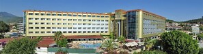 A multi-story hotel with a central courtyard and a pool area. - Kırbıyık Resort Hotel (Alanya)