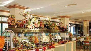 A buffet area with a variety of food items and decorative floral arrangements.