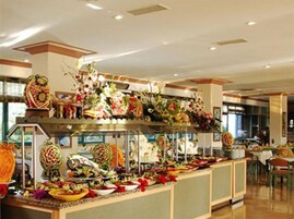 Zona de bufé con diferentes opciones de comida y arreglos florales decorativos.