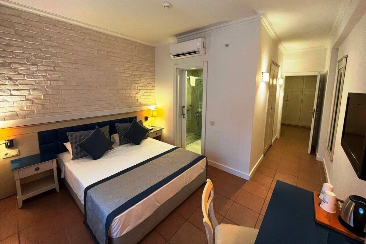 A hotel room with a large bed, a desk with a chair, a TV, and a bathroom visible through an open door.