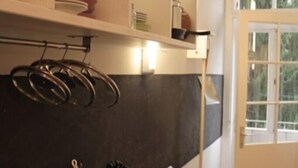 A kitchen with a black countertop, hanging pots, and utensils. There is a window with a view of greenery outside. - Altstadthaus Cityappartements (Graz)