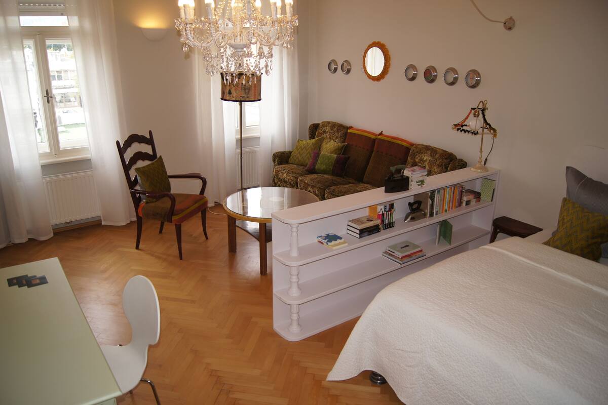 Una habitación acogedora con cama, sofá, mesa de comedor y una araña.