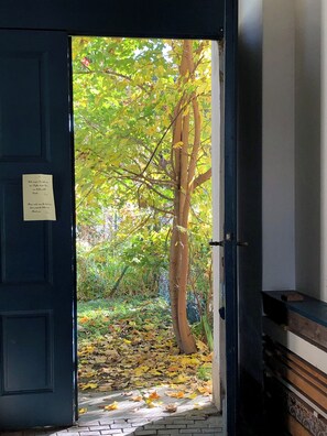 A doorway leading to a garden with a tree and fallen leaves. - Altstadthaus Cityappartements (Graz)