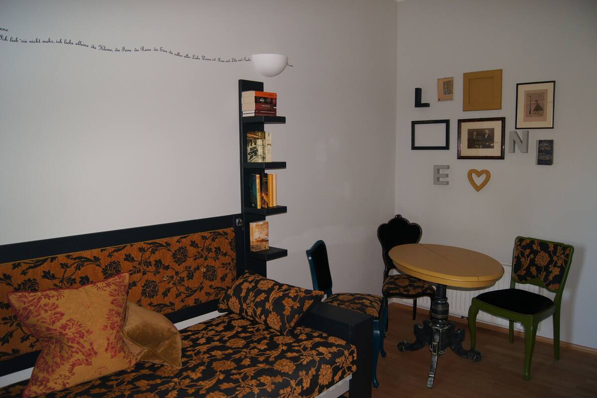 Una habitación acogedora con un sofá estampado con motivos florales, una mesita redonda y una estantería.
