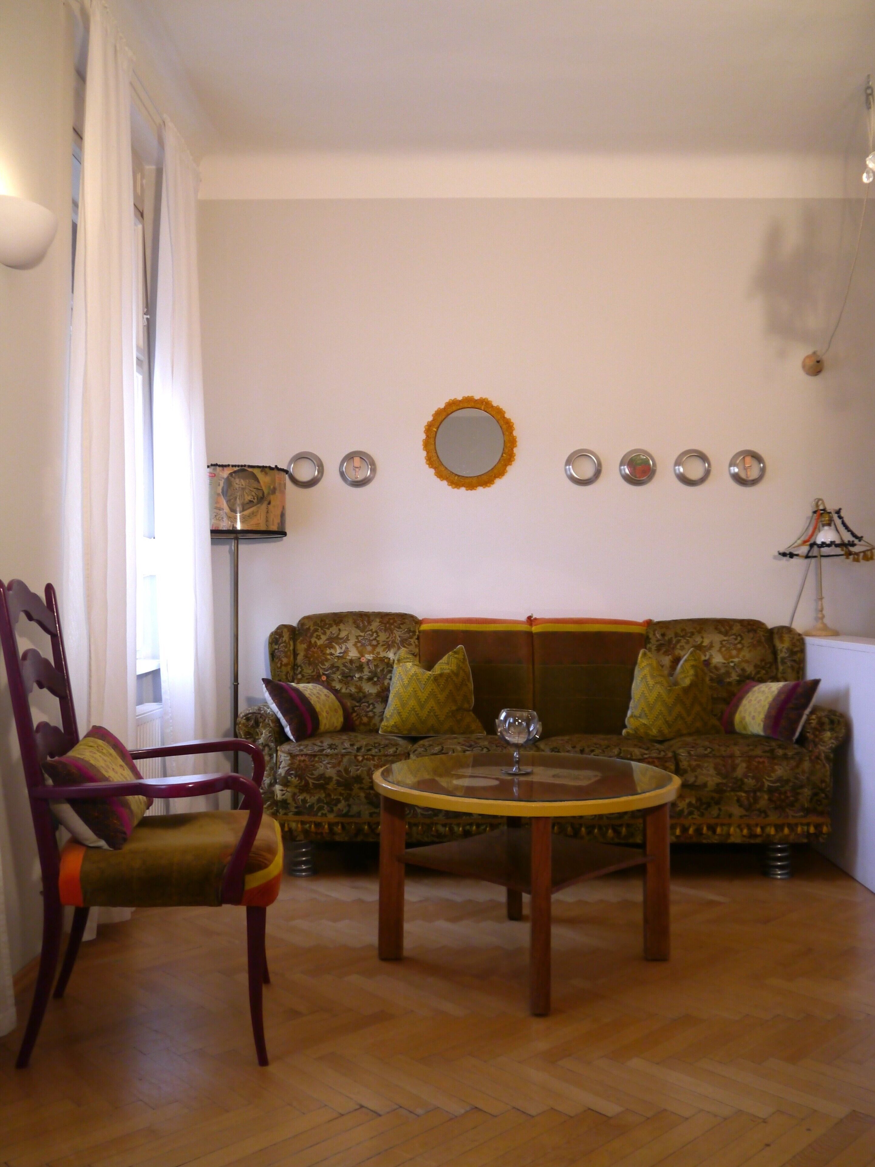 Een woonkamer met een bank, een fauteuil, een salontafel en een spiegel aan de muur.
