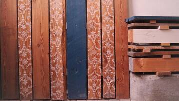 Pared de paneles de madera con un diseño decorativo, un panel azul oscuro, y una pila de tablones de madera.
