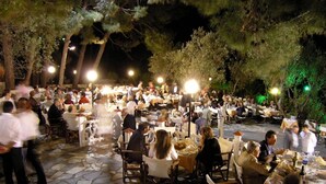 An outdoor dining area with stone flooring and tables set up for guests. - Mytilana Village Hotel (Lesvos)