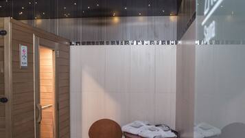 Een kleine, privé sauna met een houten deur, één stoel en een tafel met handdoeken.