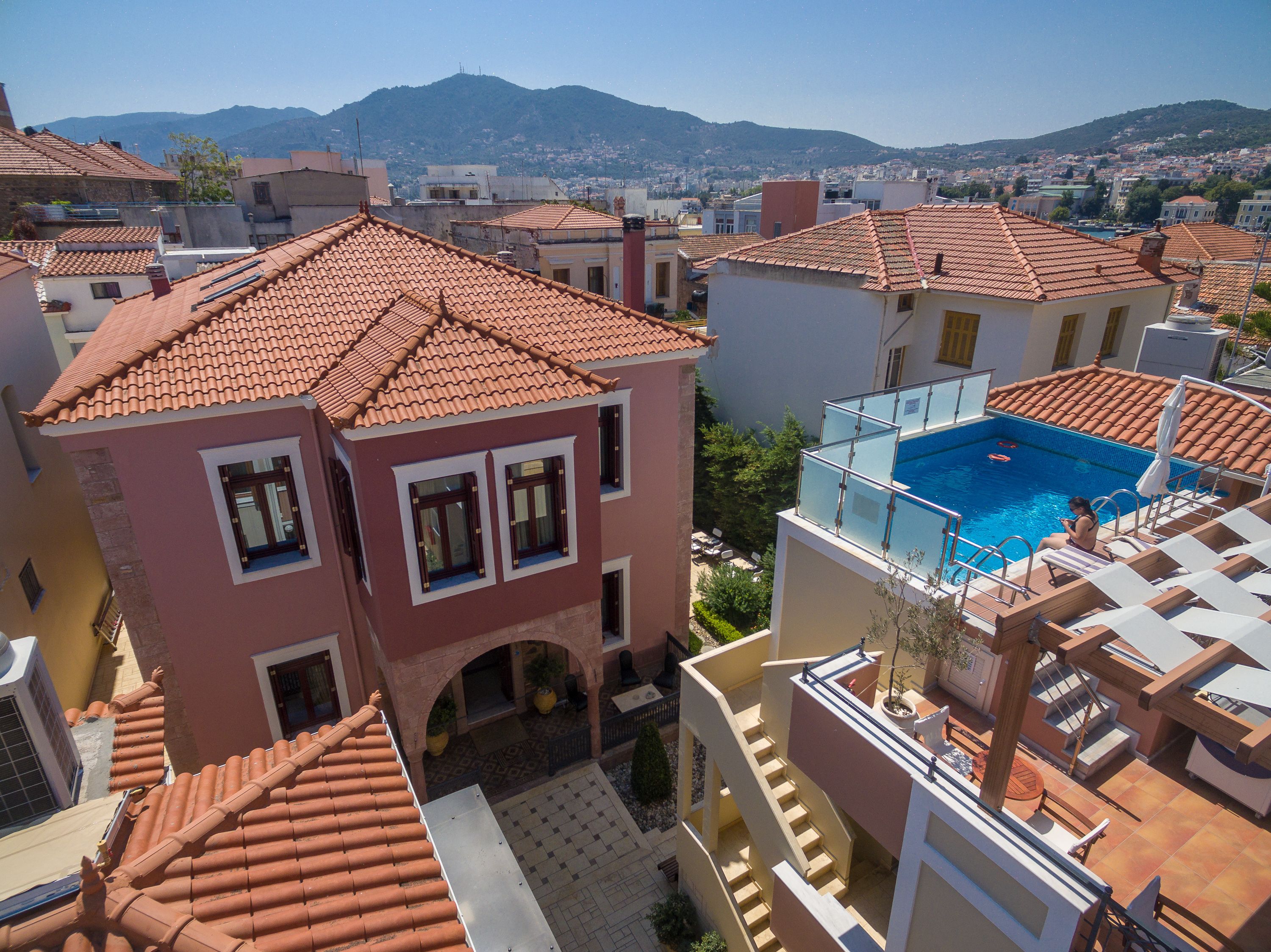 Un edificio residencial con piscina, tejados de teja y vistas a la ciudad y montañas al fondo.