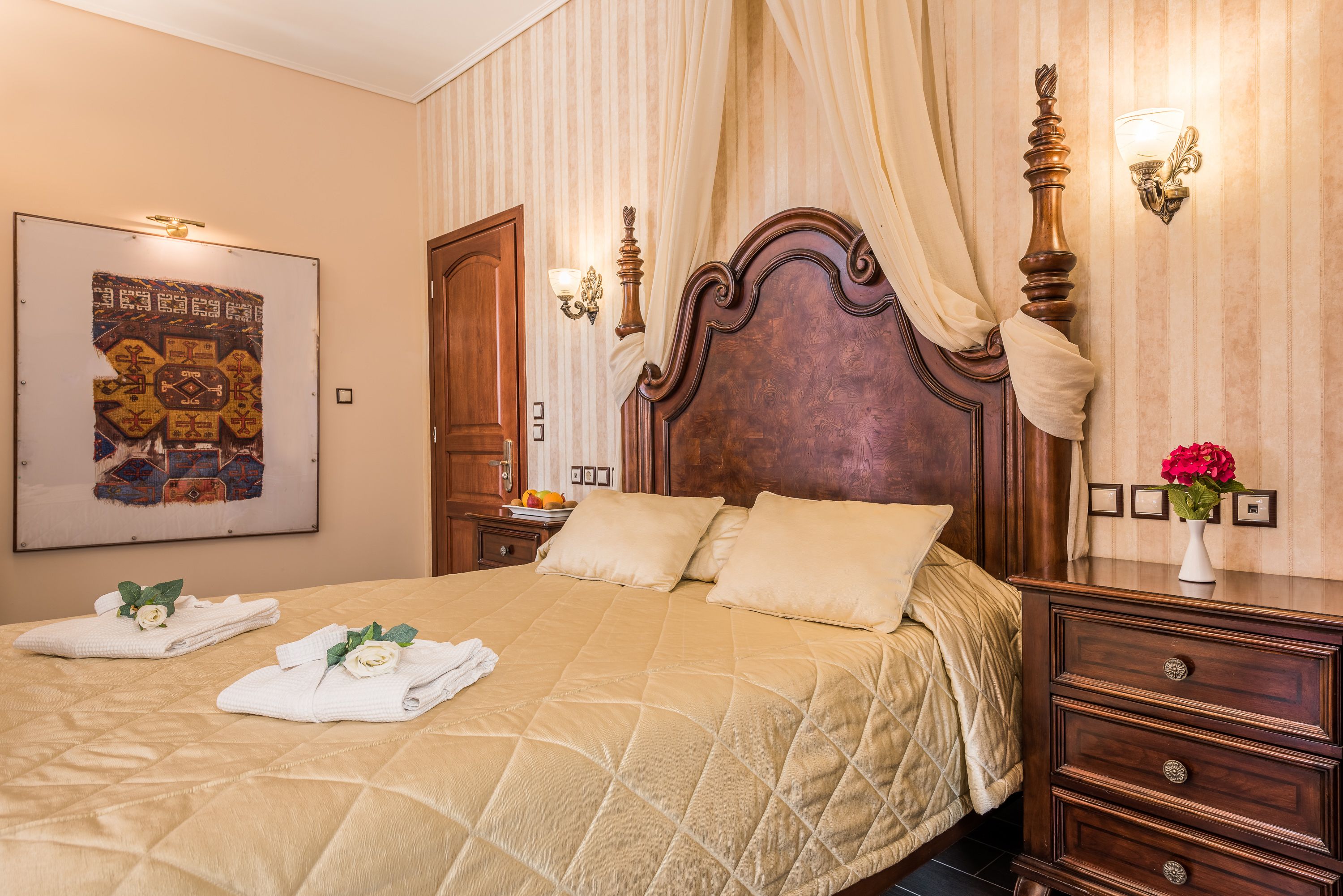 A hotel room with a large bed, a wooden headboard, a nightstand, a mirror, and a wall-mounted light fixture.