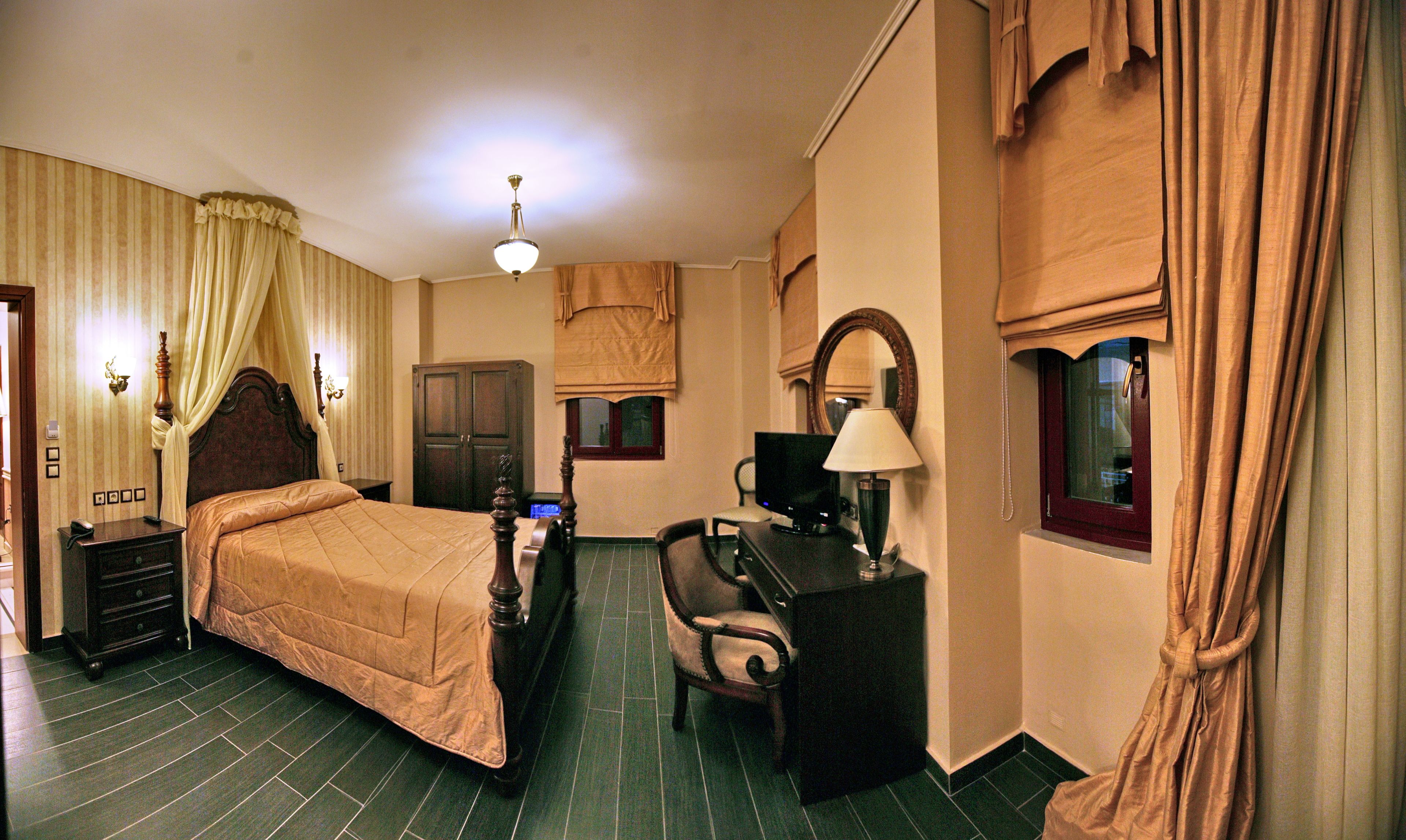 A hotel room with a bed, a desk, a chair, a television, and a lamp.